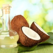 decanter with coconut oil and coconuts on green background